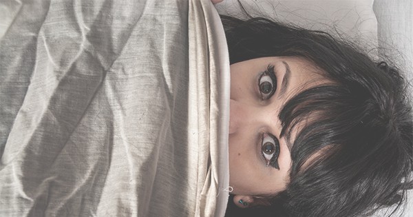 Woman hiding under bedsheet