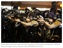 Police officers point weapons at demonstrators in Ferguson, MO